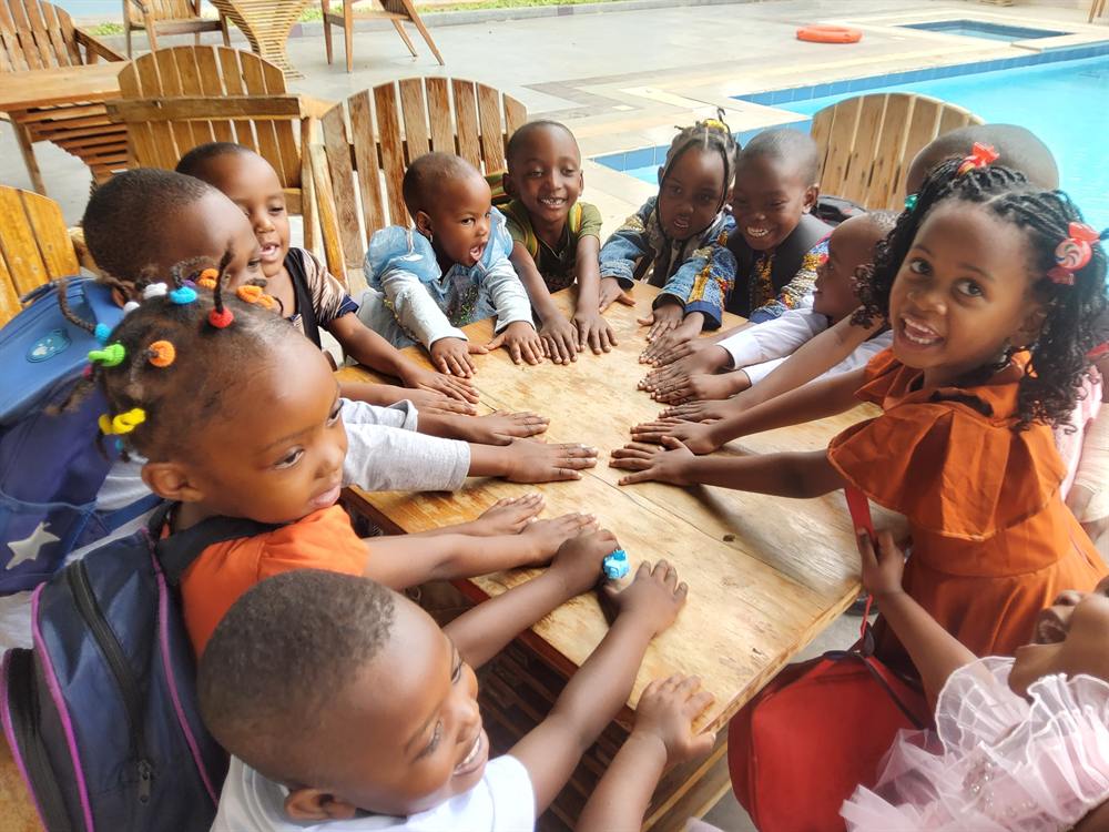 Kinder des Victory Day Care legen ihre Hände zusammen auf einen Tisch